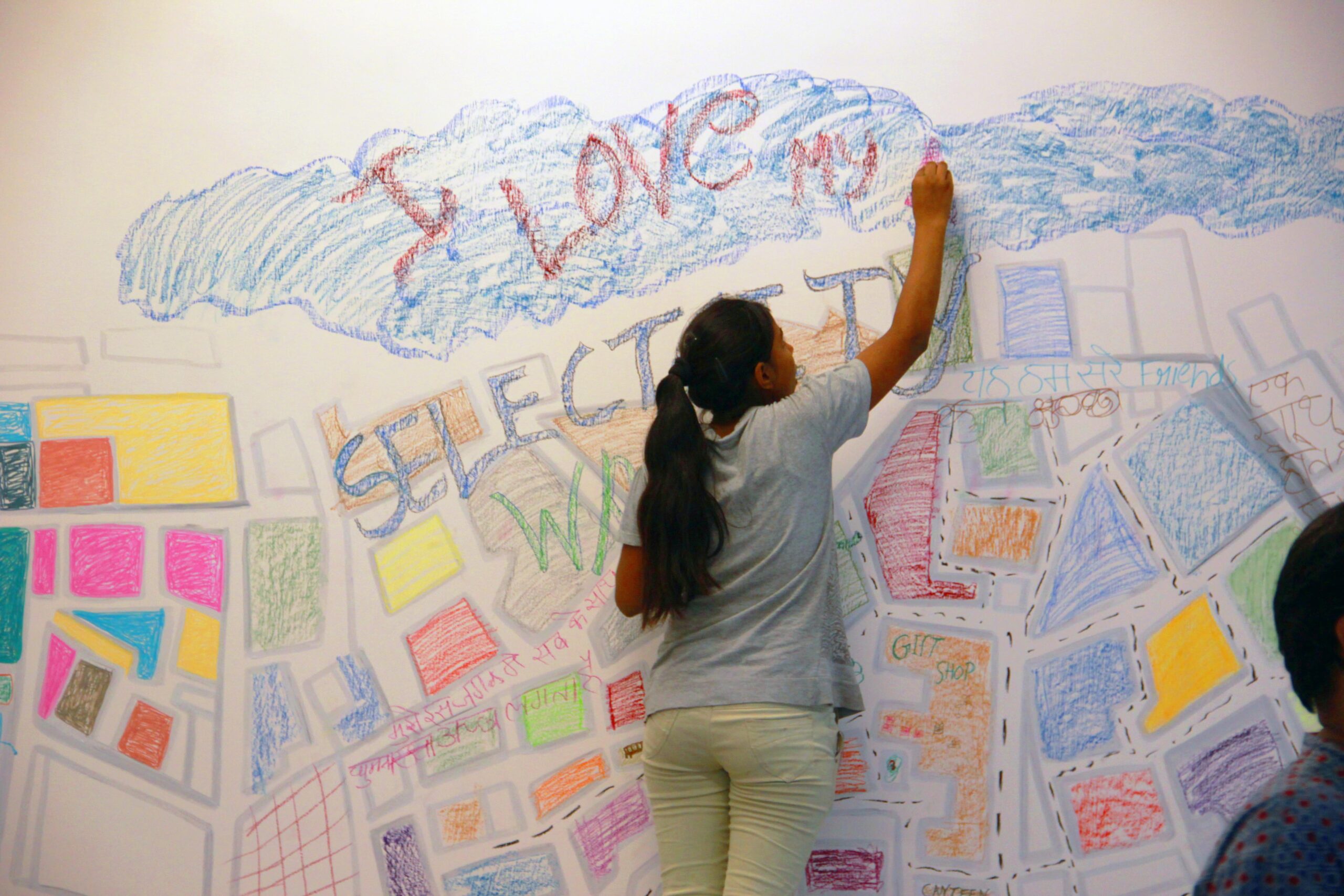 Girl writing on a colourful wall with chalk
